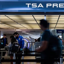 A TSA officer checks a traveler’s identification at an airport checkpoint.