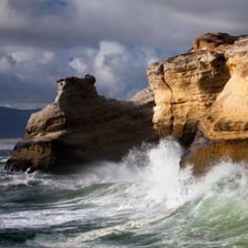 Waves wearing away a rocky coastal cliff.
