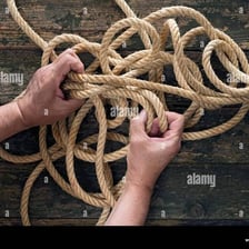 Hands pulling apart a knot in a length of rope.