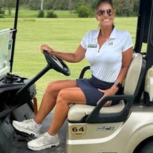 A golfer traveling in a golf cart on a golf course