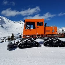 A tracked Sno-Cat snow vehicle traveling over snowy terrain