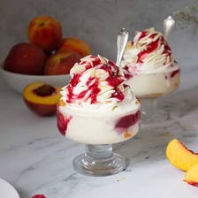 A peach Melba dessert with peaches, vanilla ice cream, and raspberry sauce.