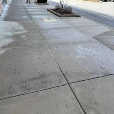 Rain falling on and wetting a paved surface.