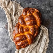 A golden challah loaf with its characteristic braided shape.
