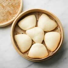 A steamed bao bun in a dim sum basket.