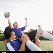 Soccer players carrying a teammate during a celebration.