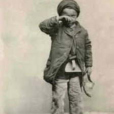 A chimney sweep with soot on their face and work clothes.