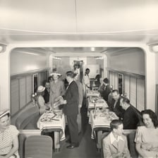 A passenger train dining car with tables and seats
