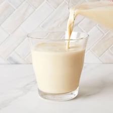 A glass of soy milk beside soybeans.