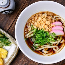 A bowl of thick Japanese udon noodles in broth.