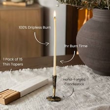 A slender taper candle standing in a candlestick.