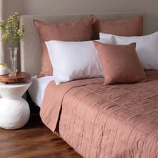 A decorative pillow sham arranged on a made bed.