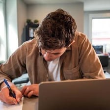 A person working at a desk with papers and a laptop.