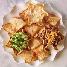 A bowl of green guacamole served with tortilla chips
