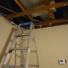 A building superintendent performing maintenance in an apartment hallway