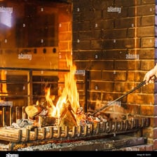 A person stirring a fire to make it burn more strongly
