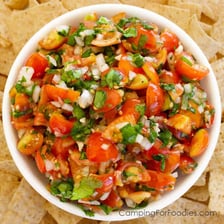 Chopped onion mixed into a bowl of fresh salsa