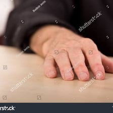 An object positioned close beside a person’s hand.