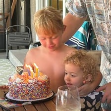 A child’s sixth-birthday cake with candles beside a clock.