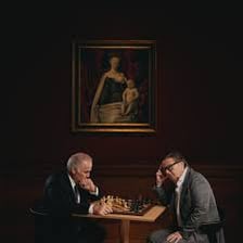 Two opponents seated across from each other during a chess game.