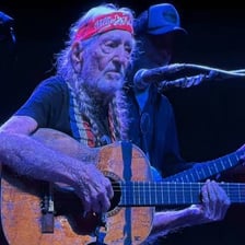 Willie Nelson performing with his guitar.