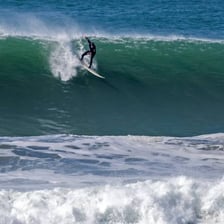 A surfer riding a wave near a beach.