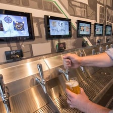 A row of beer taps dispensing different beers at a bar.