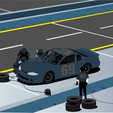 A race car stopped in a pit lane while its tires are changed