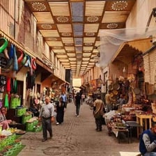 Shoppers walking among stalls in a Moroccan souk.