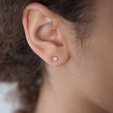 A small stud earring worn on an earlobe.