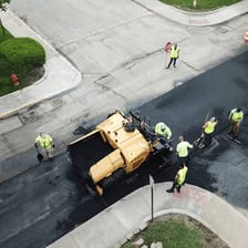 Road workers laying fresh asphalt across a parking lot