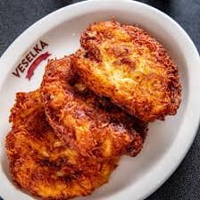 A potato latke shown beside French fries.