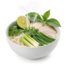 A bowl of pho with noodles, herbs, and lime wedges