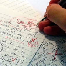 A teacher marking a student paper with a red pen