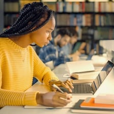 A student writing an essay at a desk