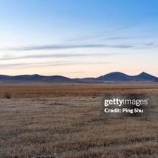A wide plain stretches toward distant mountains.