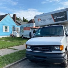 A U-Haul moving truck parked outside a house.