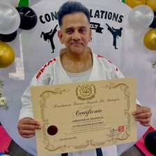 A karate practitioner wearing a black belt during a ranking ceremony.