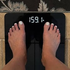 A person standing on a bathroom scale.