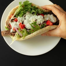 A Greek gyro served in pita bread with vegetables and sauce