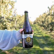 Fresh pears beside a bottle of pear cider.