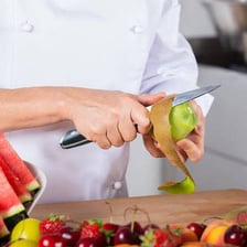 A person trimming material from an object with a knife.