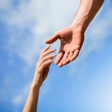 One person extending a hand to help another person stand.