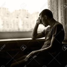 A person sitting alone with a gloomy, withdrawn expression.