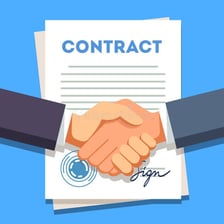 People sealing an agreement with a handshake beside a signed document