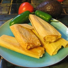 A tamal wrapped in a corn husk and prepared by steaming