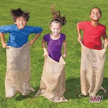 Children participating in a sack race at an outdoor picnic