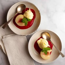 A Peach Melba dessert with peaches, ice cream, and raspberry sauce.