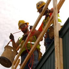 A construction worker carrying a pail at a building site