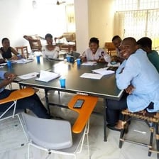 Actors seated around a table reading scripts during a rehearsal